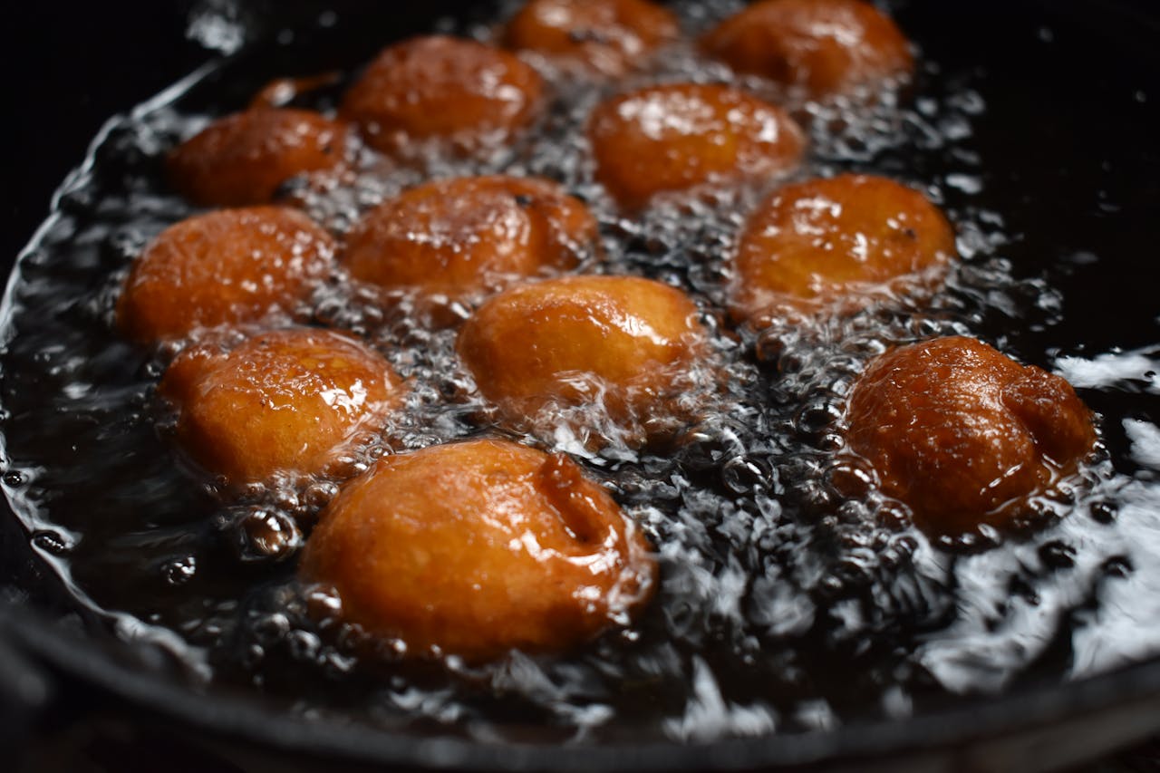Close-up of Indian sweets frying in oil, showcasing rich textures and vibrant colors.